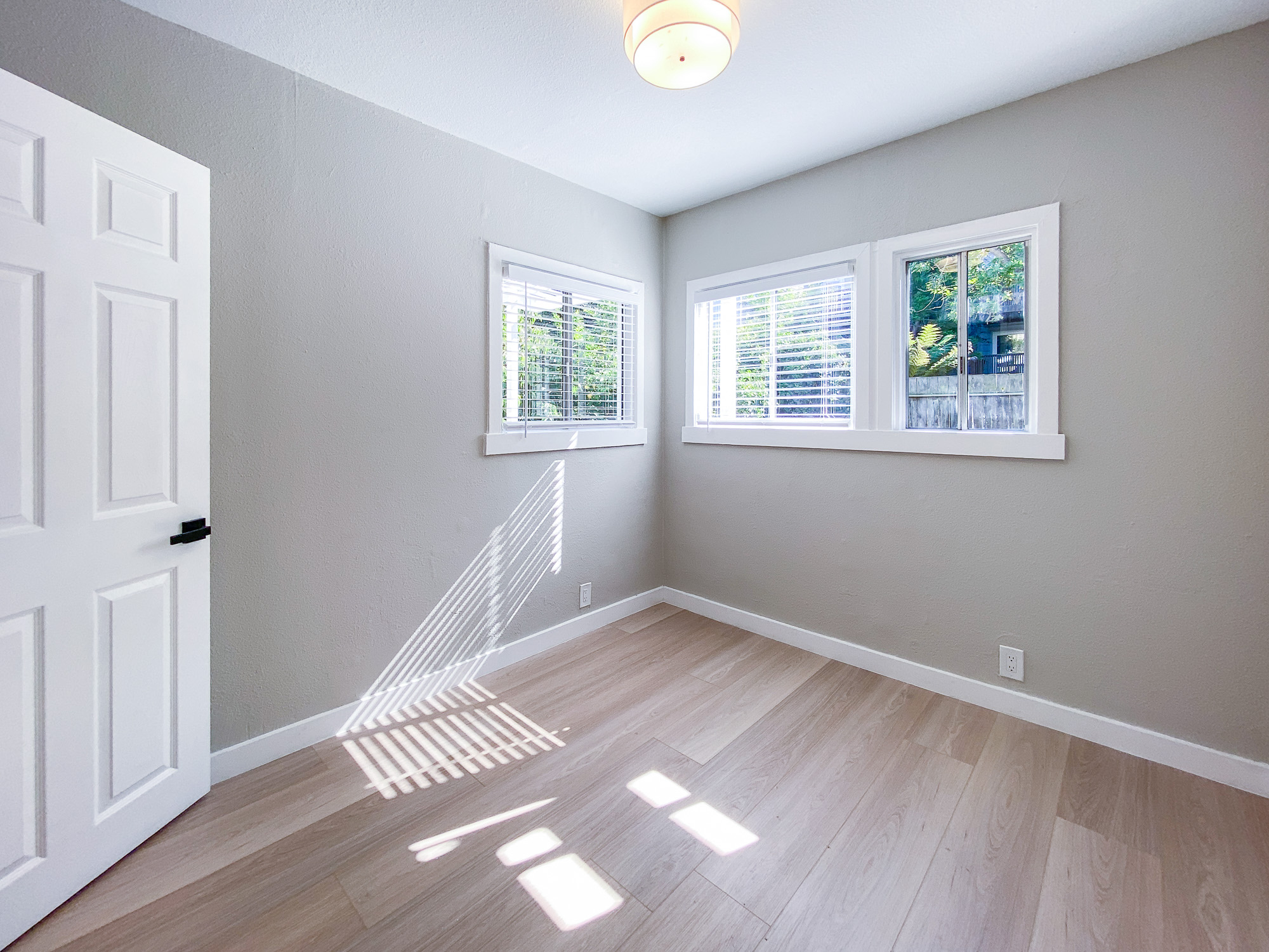 Sunlit bedroom with white oak floors and a bay window